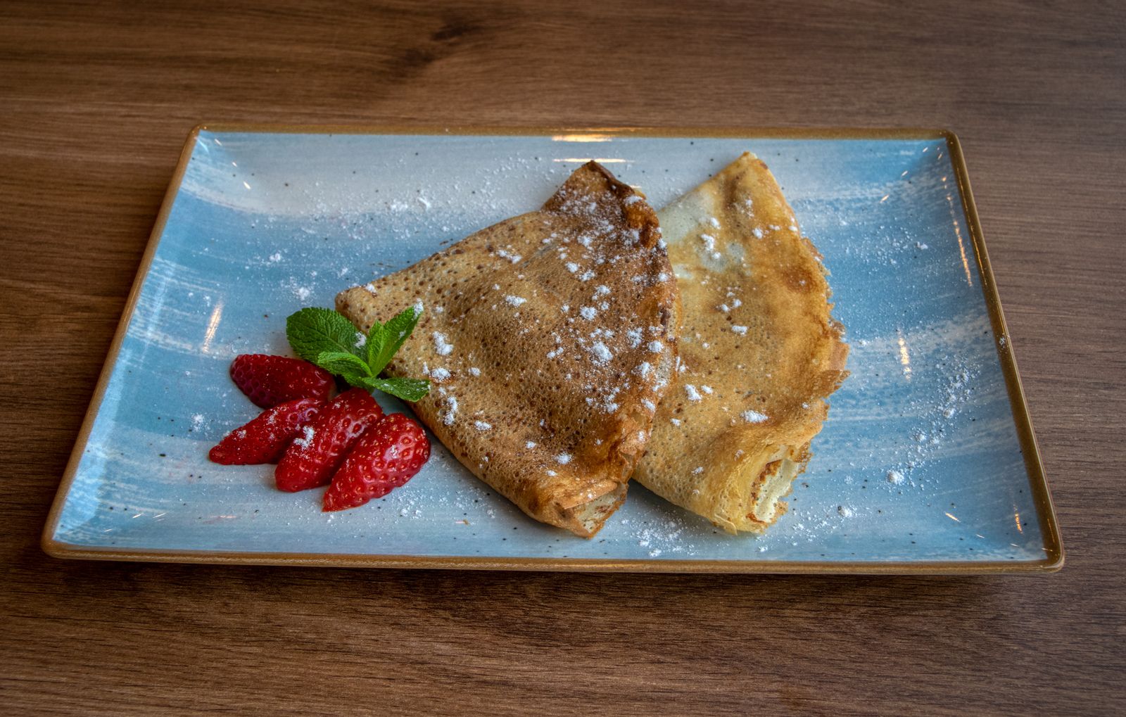 Assiette de crêpes saupoudrées de sucre glace avec des fraises